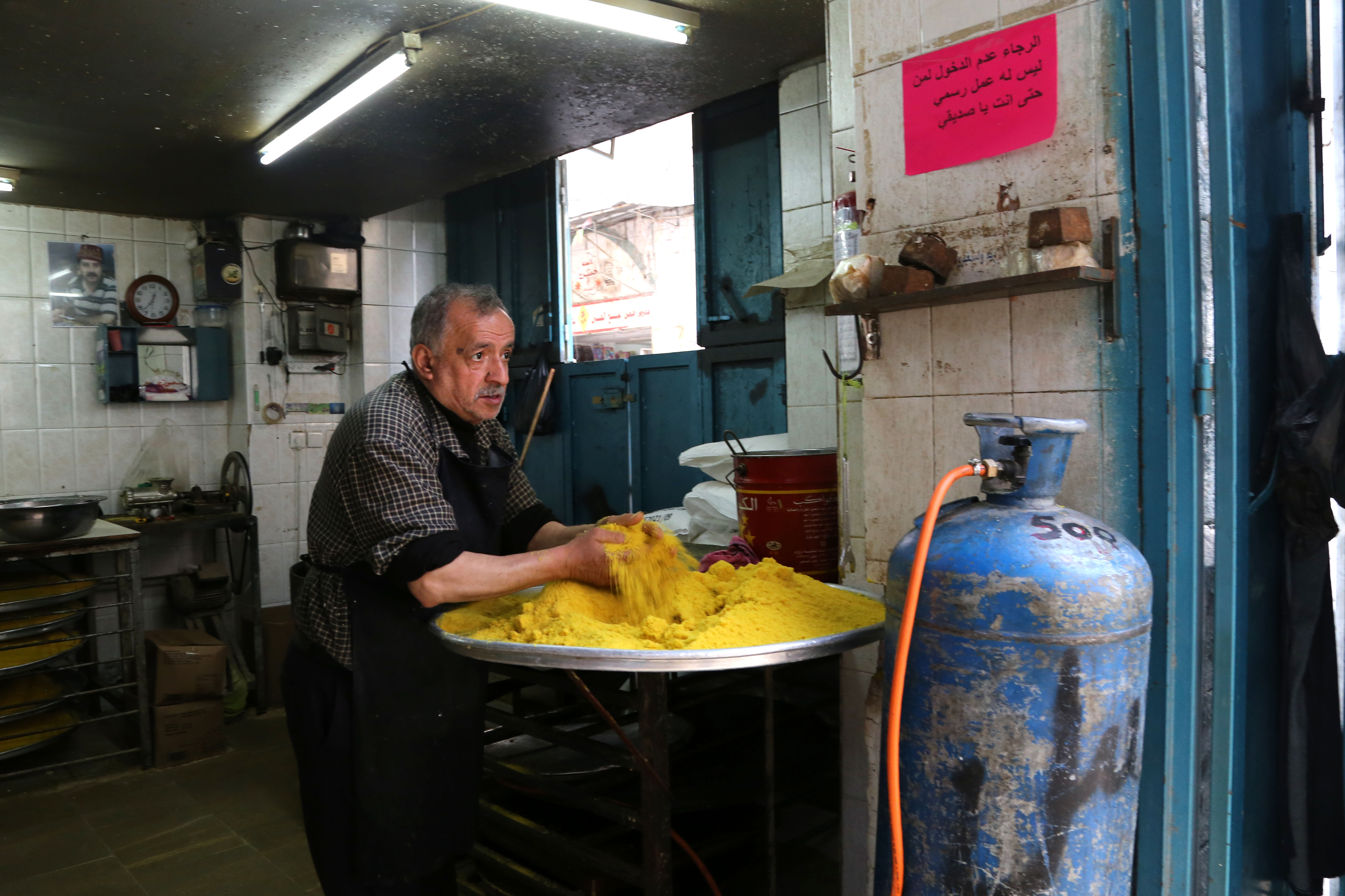 A shop owner in the old city of Nablus makes Kanafeh, a popular dessert made of soft cheese, pastry, and topped with a sugary syrup.